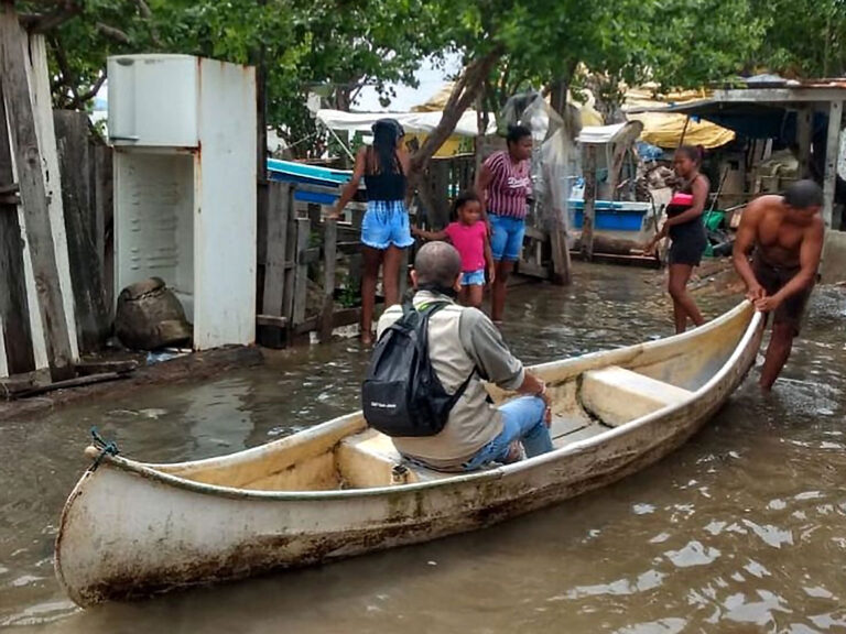 funcionario y comunidad en ambarcación por inundación