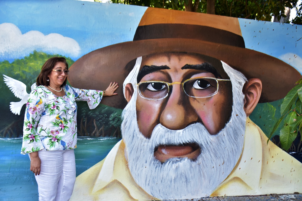 Directora junto a mural con ilustración de Rafael Vergara
